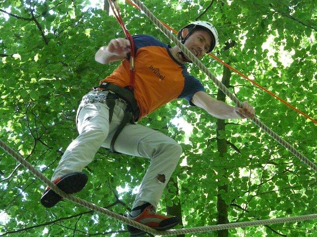 Rochester Hills Things To Do Tree Runner Adventure Park image of man in tree obstaclecourse