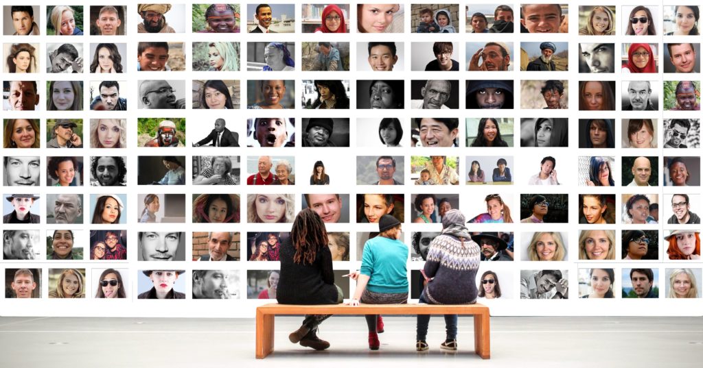 Orion Town & Civic Resources main image of 3 people sitting on a bench facing a wall grid of faces